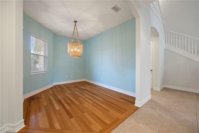 unfurnished room with light tile patterned floors and an inviting chandelier