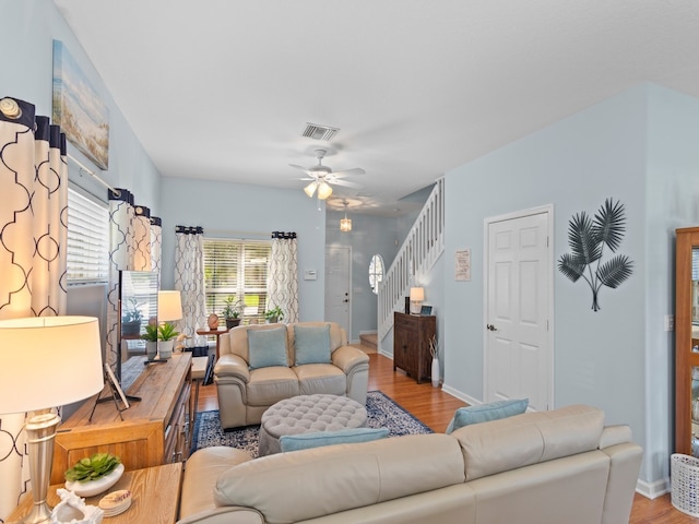 living room with visible vents, stairway, ceiling fan, and wood finished floors