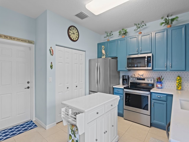 kitchen featuring visible vents, light countertops, light tile patterned floors, stainless steel appliances, and blue cabinets