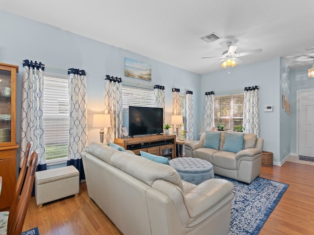 living area featuring a ceiling fan, wood finished floors, visible vents, and baseboards