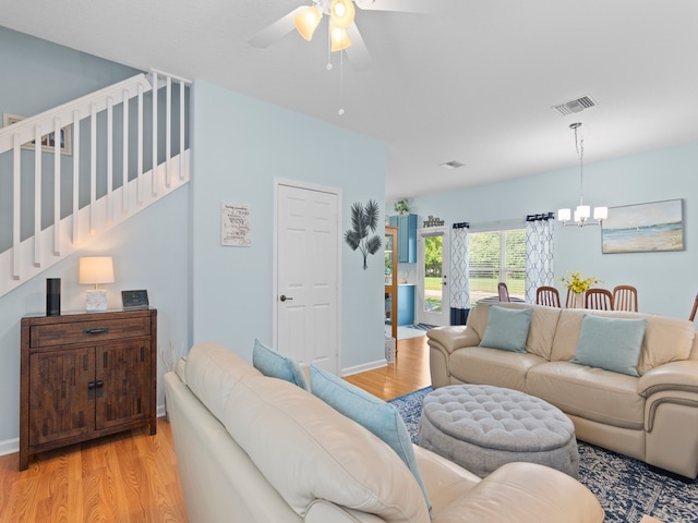 living area with visible vents, baseboards, stairs, ceiling fan with notable chandelier, and light wood-style floors