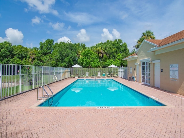 pool with a patio area, french doors, and fence