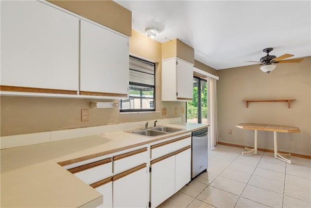 kitchen with light countertops, white cabinetry, a sink, stainless steel dishwasher, and light tile patterned floors
