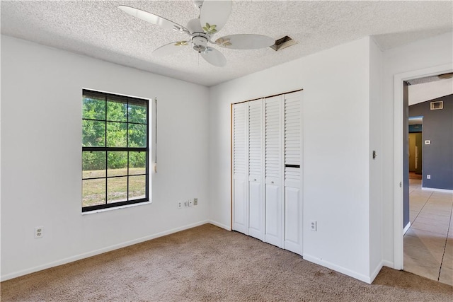 unfurnished bedroom featuring baseboards, a textured ceiling, visible vents, light carpet, and a closet