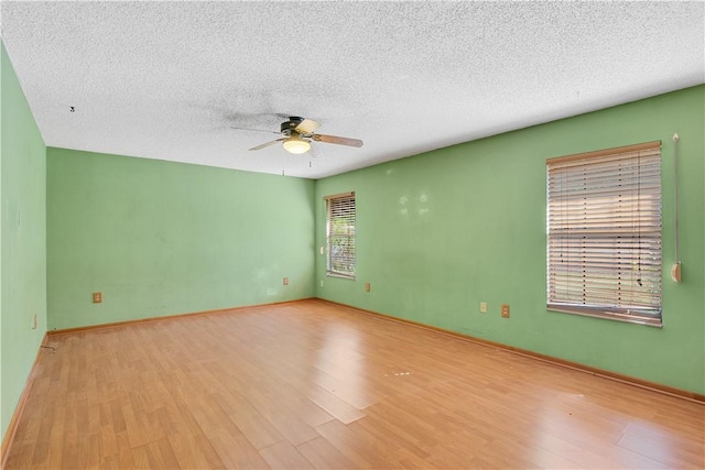 spare room featuring wood finished floors, a textured ceiling, baseboards, and ceiling fan