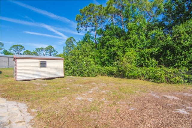view of yard featuring an outbuilding, a shed, and fence