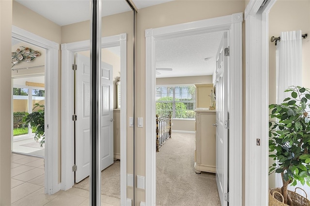 hallway featuring a textured ceiling and light colored carpet