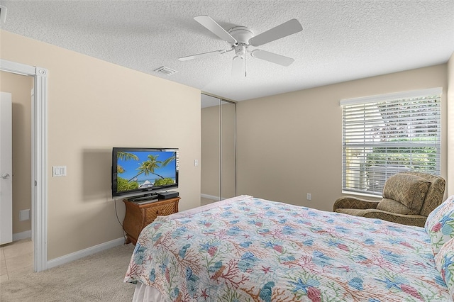 carpeted bedroom featuring ceiling fan, a closet, and a textured ceiling