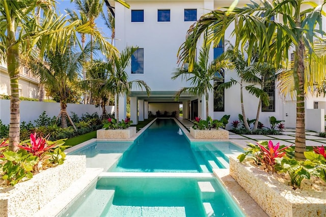 view of swimming pool with a fenced backyard and a pool with connected hot tub