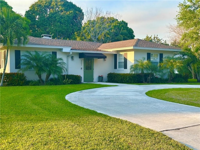 ranch-style house with stucco siding, driveway, and a front lawn