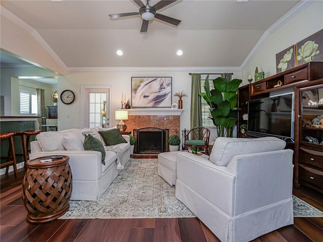 living area featuring a ceiling fan, wood finished floors, a high end fireplace, ornamental molding, and vaulted ceiling