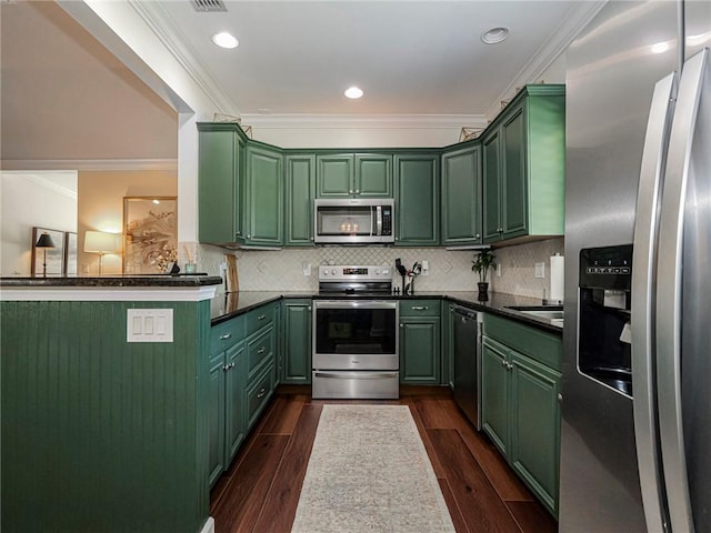 kitchen featuring backsplash, dark wood-style floors, appliances with stainless steel finishes, green cabinets, and crown molding