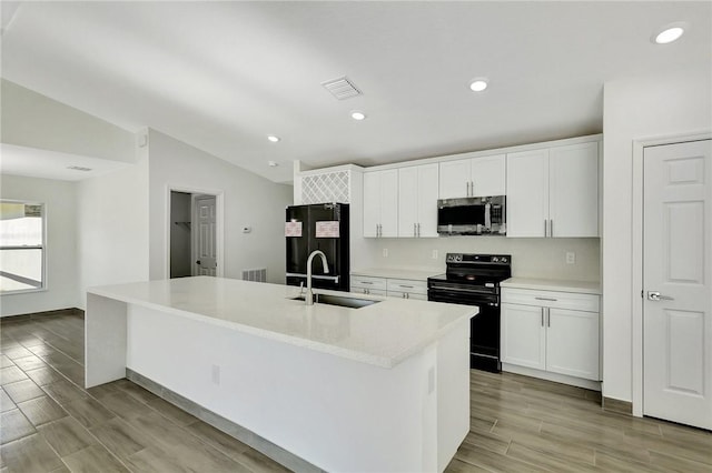 kitchen featuring white cabinets, sink, an island with sink, and black appliances