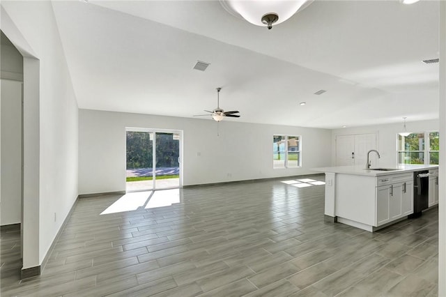 kitchen featuring lofted ceiling, sink, white cabinetry, a center island with sink, and dishwasher