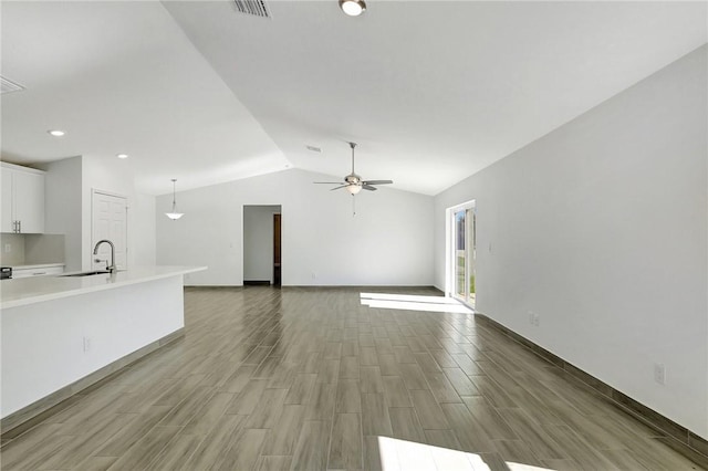 unfurnished living room featuring vaulted ceiling, ceiling fan, wood-type flooring, and sink