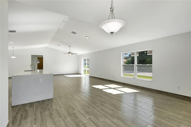 unfurnished living room featuring sink, vaulted ceiling, and ceiling fan