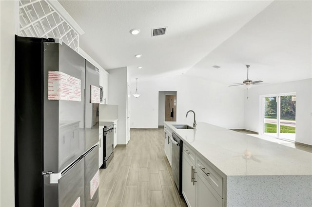 kitchen with sink, stainless steel appliances, white cabinets, a center island with sink, and vaulted ceiling