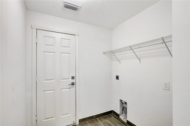 laundry room featuring dark hardwood / wood-style floors, hookup for an electric dryer, and a textured ceiling