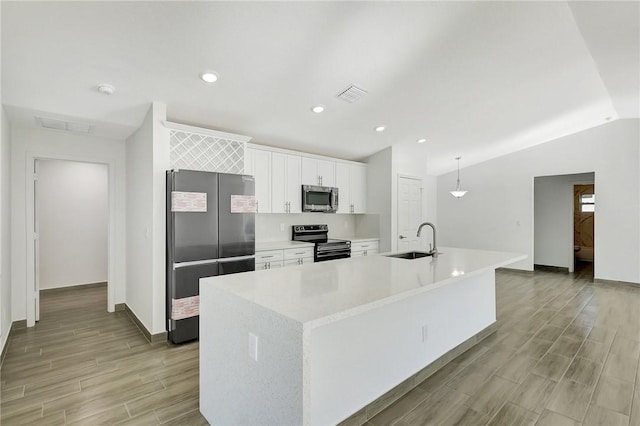 kitchen featuring stainless steel appliances, hanging light fixtures, sink, and a center island with sink