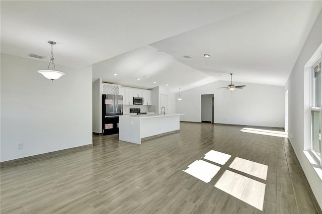 unfurnished living room featuring light hardwood / wood-style flooring, sink, vaulted ceiling, and ceiling fan