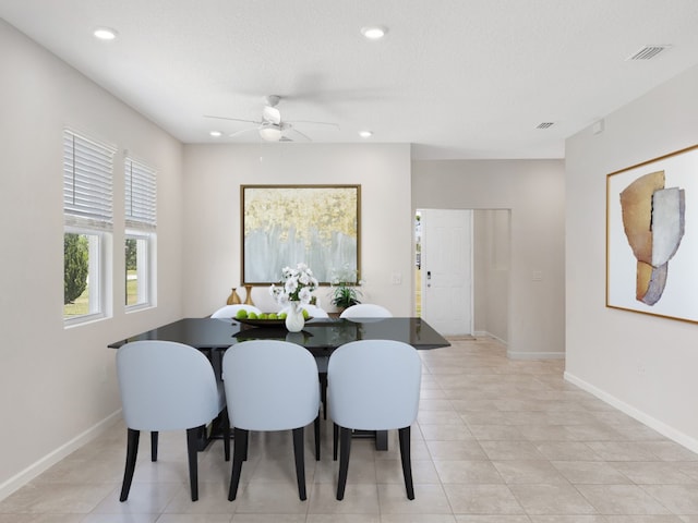 tiled dining space with a textured ceiling and ceiling fan