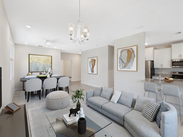 living room featuring sink and ceiling fan with notable chandelier