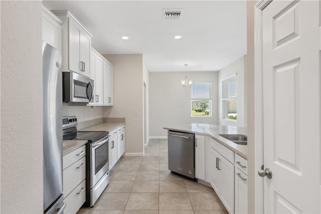 kitchen with white cabinetry, appliances with stainless steel finishes, light tile patterned floors, and decorative light fixtures