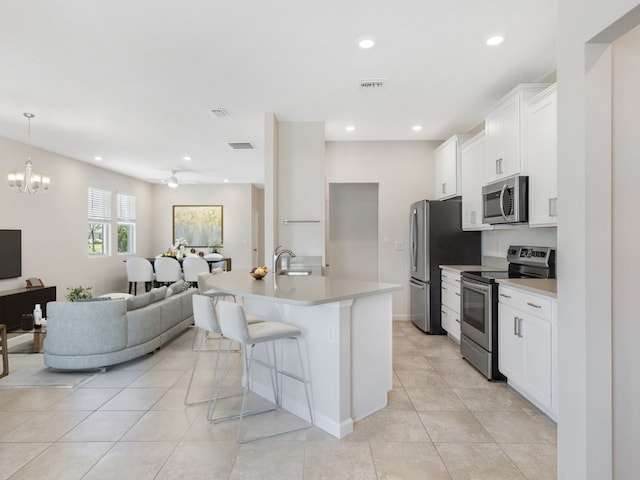 kitchen featuring appliances with stainless steel finishes, white cabinets, hanging light fixtures, sink, and a breakfast bar area