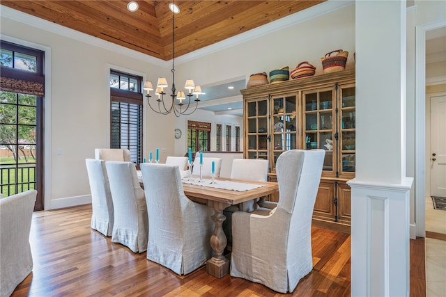 dining room with ornate columns, wood-type flooring, ornamental molding, and an inviting chandelier