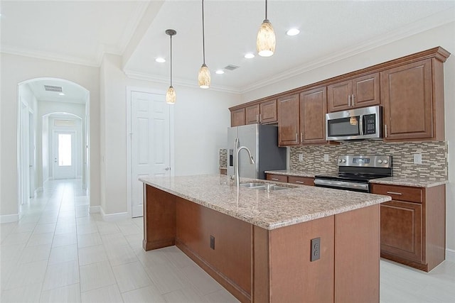 kitchen with light stone counters, pendant lighting, decorative backsplash, a center island with sink, and appliances with stainless steel finishes