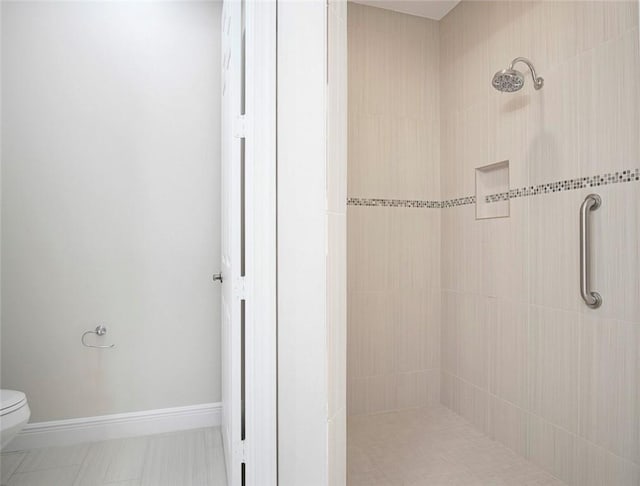 bathroom with a tile shower and toilet