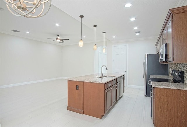 kitchen featuring appliances with stainless steel finishes, ceiling fan with notable chandelier, a kitchen island with sink, sink, and decorative light fixtures