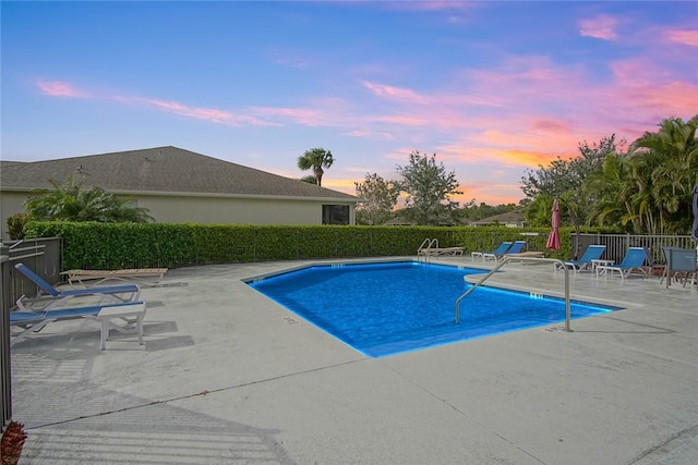 pool at dusk featuring a patio