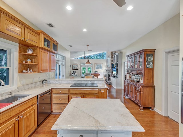 kitchen featuring black electric stovetop, hanging light fixtures, stainless steel dishwasher, a kitchen island, and light wood-type flooring