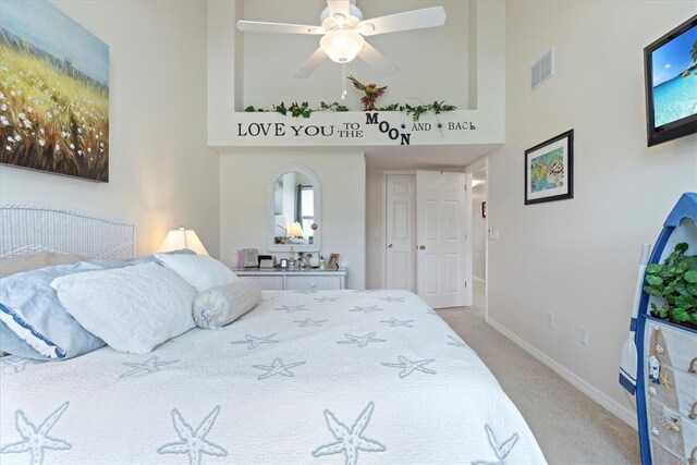 carpeted bedroom featuring ceiling fan and a high ceiling