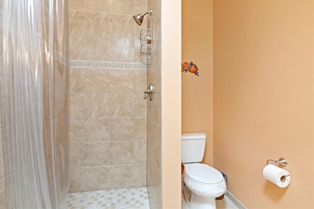 bathroom with toilet and a tile shower