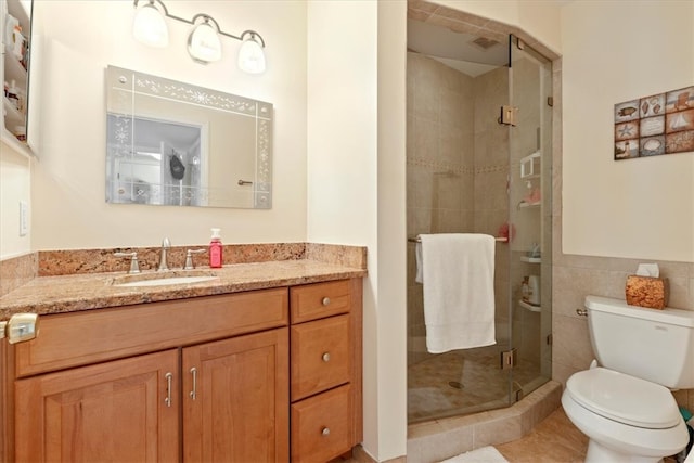 bathroom featuring tile walls, tile patterned floors, walk in shower, vanity, and toilet