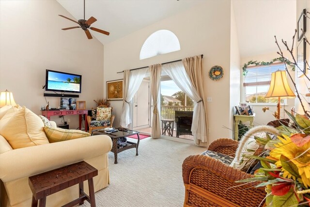 carpeted living room with high vaulted ceiling, ceiling fan, a healthy amount of sunlight, and a fireplace