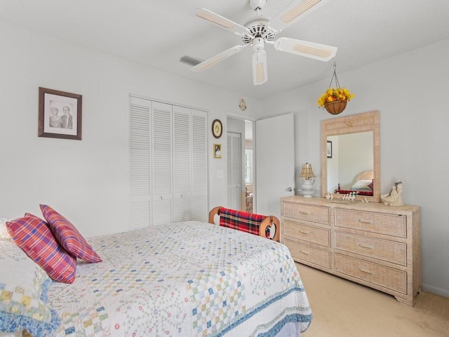 bedroom featuring a ceiling fan, visible vents, a closet, and light colored carpet