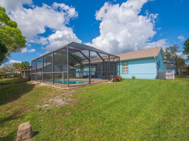 rear view of house with an outdoor pool, a lanai, central AC, and a lawn