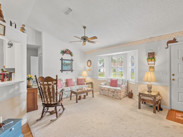 living area with a textured ceiling, ceiling fan, lofted ceiling, carpet flooring, and visible vents