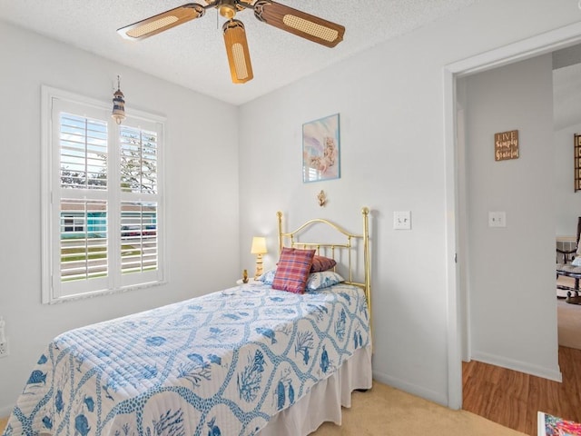 bedroom featuring a ceiling fan, a textured ceiling, and baseboards