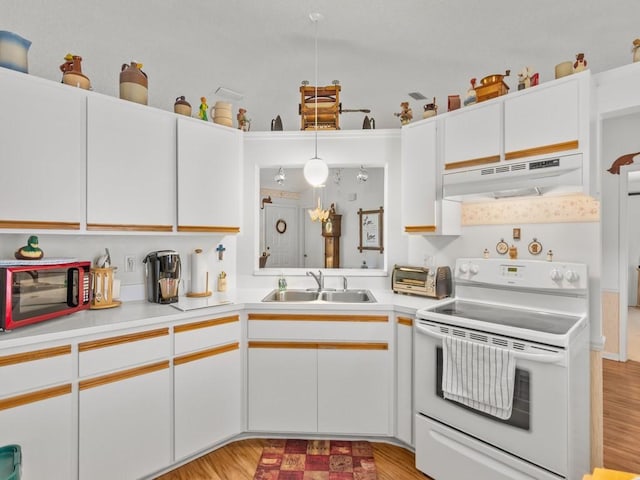 kitchen with electric stove, light wood-style flooring, light countertops, under cabinet range hood, and a sink