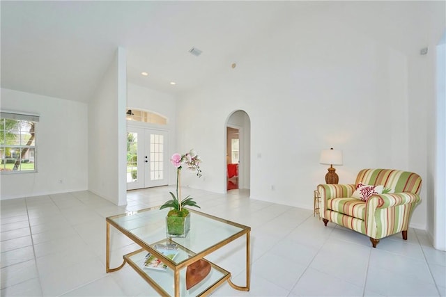 living area with light tile patterned floors, visible vents, recessed lighting, arched walkways, and french doors