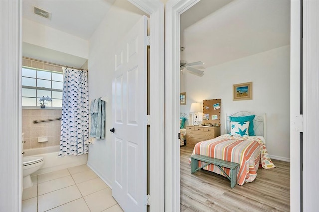 bathroom with tile patterned flooring, visible vents, toilet, shower / bath combo with shower curtain, and a ceiling fan