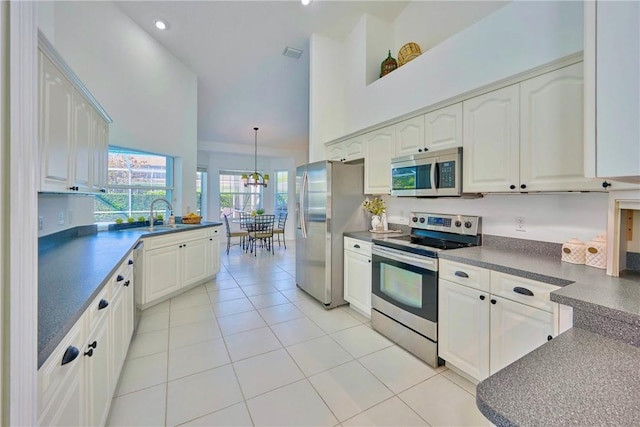 kitchen featuring visible vents, dark countertops, stainless steel appliances, light tile patterned floors, and a towering ceiling