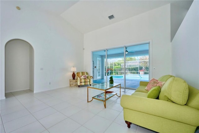 living area featuring baseboards, visible vents, high vaulted ceiling, arched walkways, and a sunroom