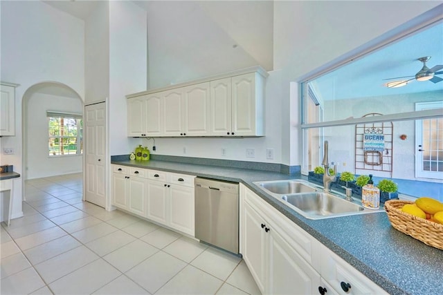 kitchen featuring light tile patterned flooring, a sink, a towering ceiling, and stainless steel dishwasher