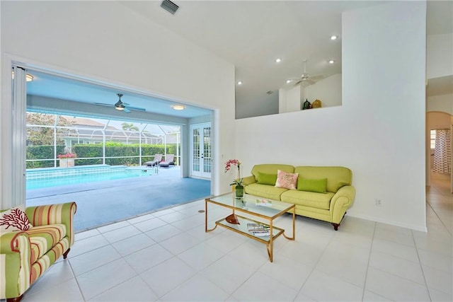 living area with visible vents, a towering ceiling, a ceiling fan, and a sunroom