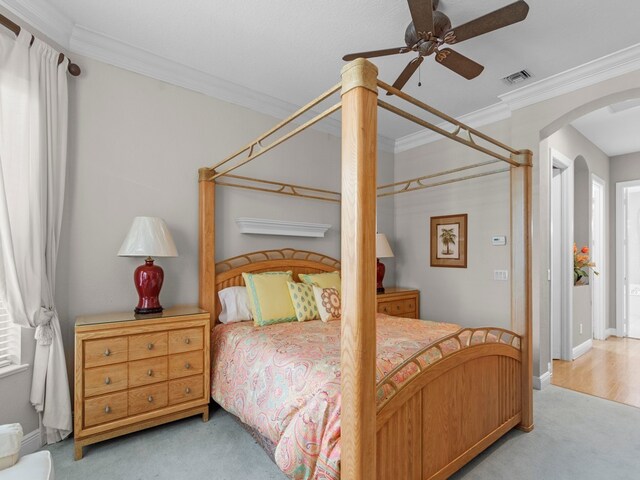 carpeted bedroom featuring ceiling fan and crown molding